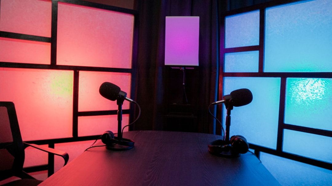 a-table-with-a-lamp-and-a-chair-in-a-room-with-windows-zmc6lpgk8u4